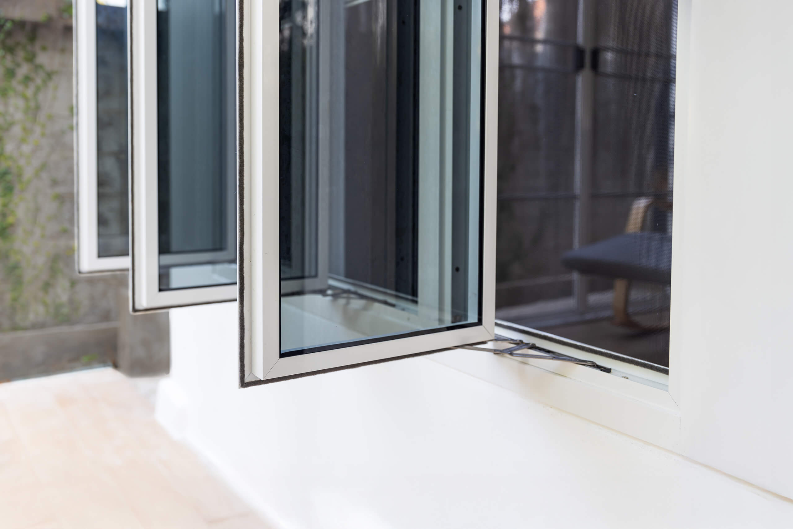 Open casement windows on a white wall, allowing natural cross-ventilation.